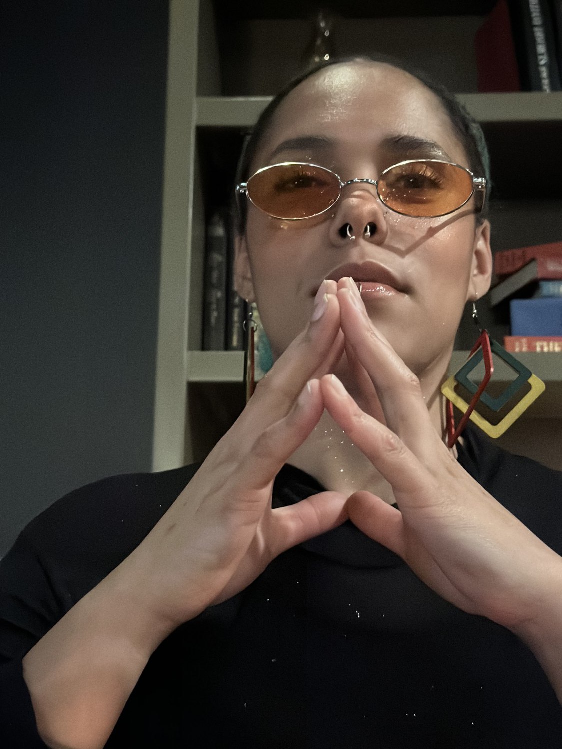 Izze Babb, leasing agent at Aspenleaf Apartments, wearing orange-tinted sunglasses and bold geometric earrings