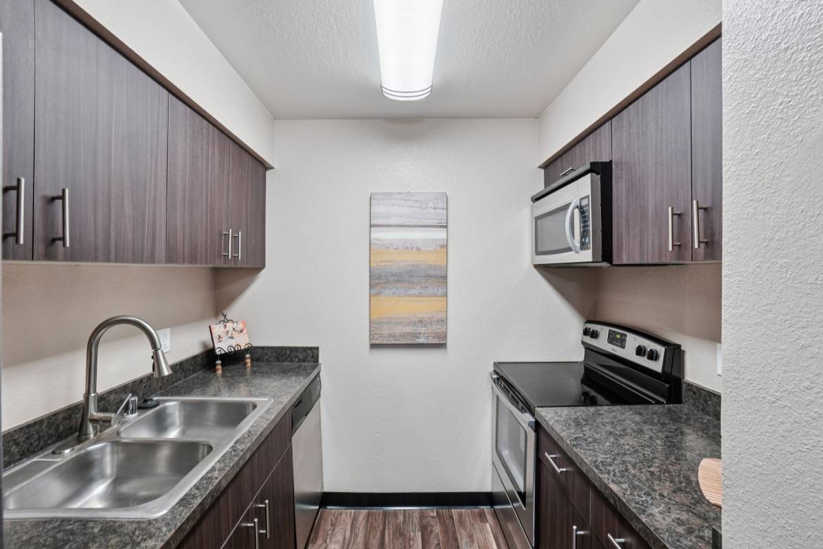 Renovated galley kitchen with dark cabinetry, from Unit 2's listing